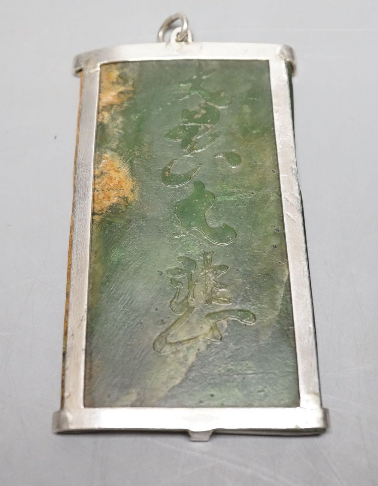 A Chinese carved spinach green jade panel, 9cms high.